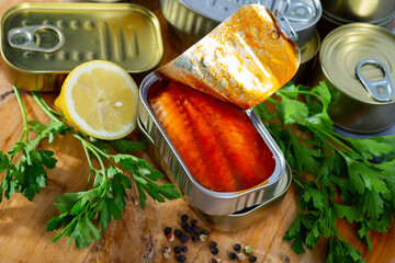 Canned sea fish, mackerel fillets in tomato served with herbs and lemon on wooden table