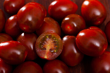 Ripe red cultivated species kumato tomatoes on wooden background. Healthy vitamin product