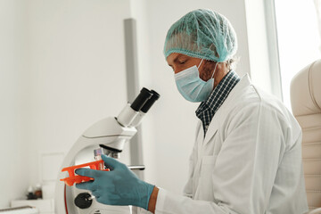 Biochemical research scientist working with microscope in pharmaceutical research labolatory