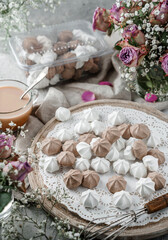 Fototapeta na wymiar White and chocolate meringues, zephyr, on lace napkin with cup of coffee and rose flowers on light background. Sweets, dessert and pastry, homemade cakes, top view, selective focus