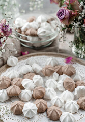 Fototapeta na wymiar White and chocolate meringues, zephyr, on lace napkin with cup of coffee and rose flowers on light background. Sweets, dessert and pastry, homemade cakes, close up, selective focus