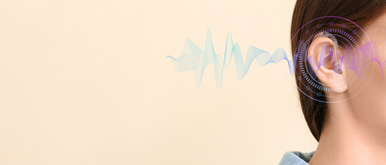 Young woman with hearing aid on color background