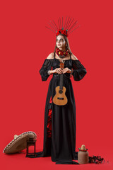 Young woman with painted skull on her face and guitar against red background. Celebration of Mexico's Day of the Dead (El Dia de Muertos)