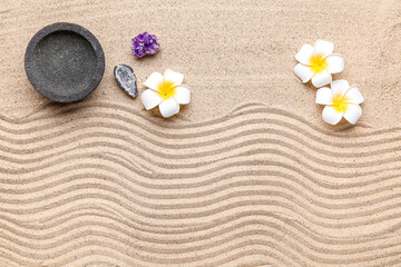 Bowl, crystals and plumeria flowers on sand with lines. Zen concept