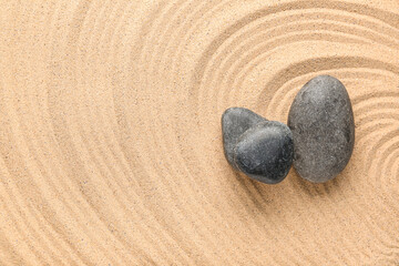 Black spa stones on sand with lines, closeup. Zen concept