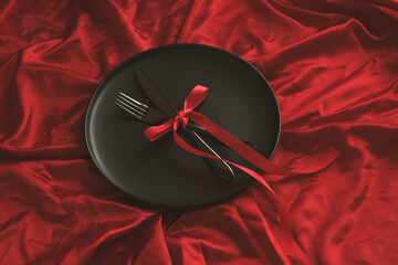 There is a plate with cutlery on a red background. Holiday concept