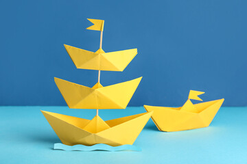 Tower of paper origami boats on color background