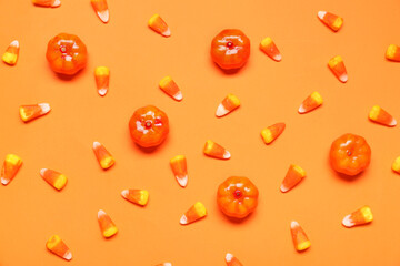 Candy corns and pumpkins on orange background
