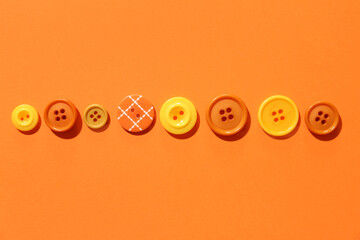 Colorful sewing buttons on orange background