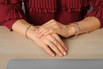 Hands of mature woman with stylish accessories on table in office, closeup