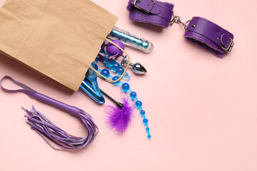 Shopping bag with different sex toys on pink background