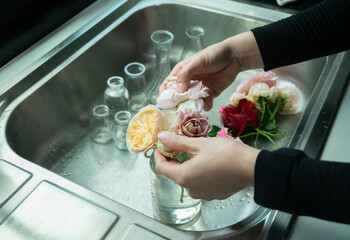 Woman arranging various roses in glass vase. Roses are best known as ornamental plants grown for...