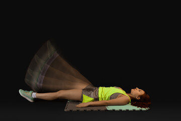 Young fitness trainer in motion on dark background