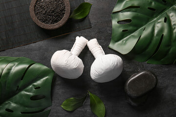 Beautiful spa composition with herbal bags, sea salt and stones on black background