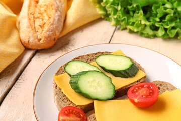 Tasty sandwiches with cheese, tomato and cucumber in plate on light wooden background, closeup