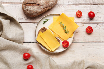 Tasty sandwich with cheese and tomatoes on light wooden background
