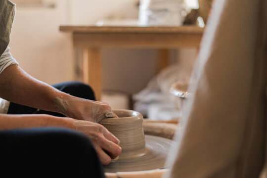 An Up-close, Personal Perspective Of A Potter's Hands As They Carefully Shape A Clay Vessel On A Pottery Wheel