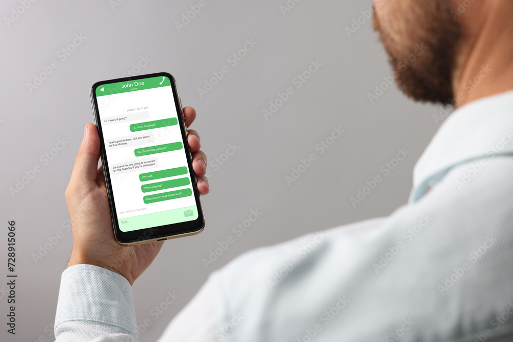 Aufkleber man texting with friend using messaging application on smartphone against grey background, closeup