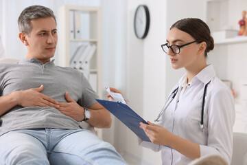 Gastroenterologist with clipboard consulting patient in clinic