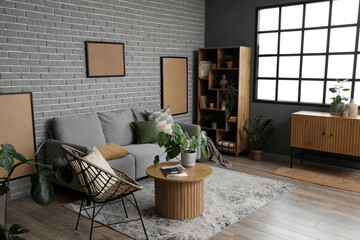 Interior of modern living room with cozy grey sofa, coffee table and chair near brick wall