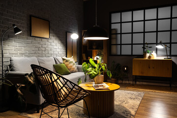 Interior of modern living room with grey sofa, wooden coffee table and glowing lamps at evening