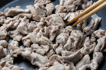 豚肉(もも切り落とし)をフライパンで炒める調理シーン。