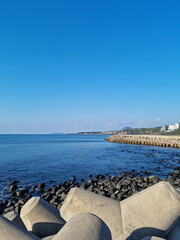 Fototapeta na wymiar The blue Jeju sea with a breakwater.