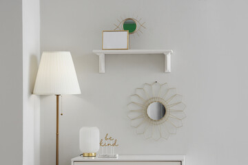 Chest of drawers with lamp, mirror and decor near white wall