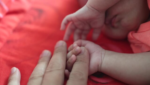New born baby hand holding father hand during baby sleeping. newborn baby and dad hands. father taking care of his daughter kid happy family dream of health
