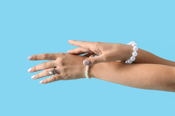 Hands of young woman with ring and bracelets on blue background