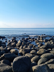 Fototapeta na wymiar This is a Jeju beach with blue skies and basalt rocks.