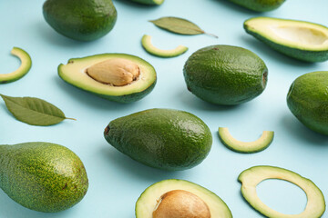 Fresh ripe avocados and leaves on blue background