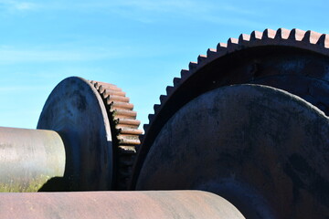 Old gearing or locomotive against clear blue sky.