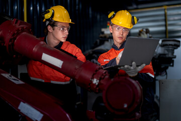 group of male engineer workers maintenance automatic robotic arm machine in a dark room factory. worker checking and repairing automatic robot hand machine. Worker wearing safety glasses and helmet.