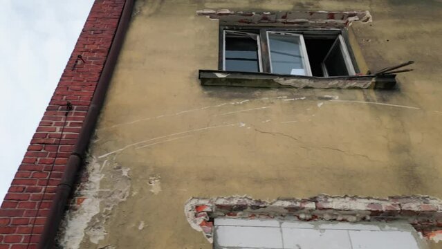 Low angle dolly movement shot on broken windows of a crumbling abandoned building