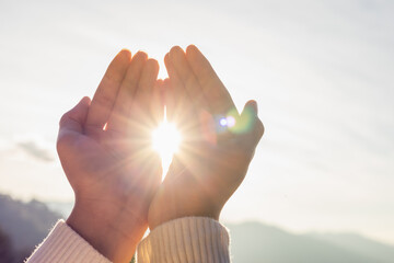 Woman hands holding the sun at dawn.spirituality concept.