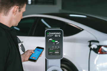 Young man travel with EV electric car to shopping center parking lot charging in downtown city...