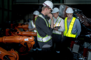 Sales manager and factory owner in suits negotiating selling robots used in the factory. Business engineers meeting and checking new machine robot. Workers walking at warehouse welding machine.