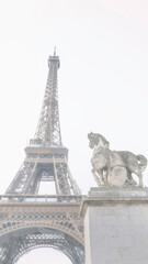Fototapeta na wymiar The Eiffel Tower and The statue of Pegasus, an equestrian statue called Mercure Monte sur Pegase, in soft foggy tone in Paris, France