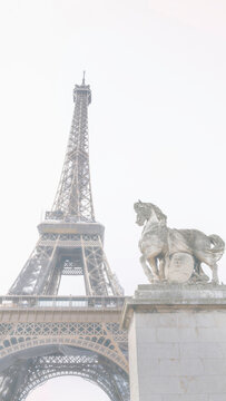 The Eiffel Tower and The statue of Pegasus, an equestrian statue called Mercure Monte sur Pegase, in soft foggy tone in Paris, France