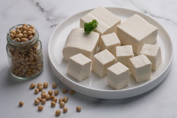 tofu or bean curd is traditional food made from soybean. sliced tofu on white plate on white marble table. tahu putih.