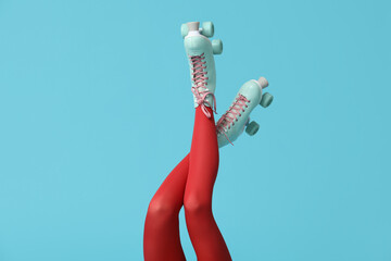 Legs of beautiful young woman in vintage roller skates on blue background