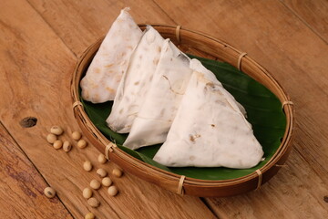 Raw tempeh or tempe. tempeh slices in woven bamboo container on wooden table. raw soybean seeds next to tempeh. Tempe is a traditional Indonesian food made from fermented soybeans.