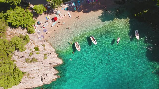 Sunbathers and boats populate the coastline in Brela Punta Rata Beach, Croatia. The Riviera's charm is amplified by its lively summer buzz.
