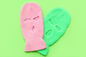 Stylish balaclavas on green background