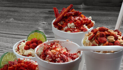 group of Mexican snacks, several corns in cups, prepared with chili, peanuts, chips, chamoy sauce, delicious