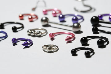 Composition with different jewelry for piercing on light background, closeup