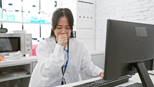Worried young chinese woman scientist, unwell, coughing in lab coat &ndash; could it be bronchitis or just a cold? health care alert inside the laboratory!
