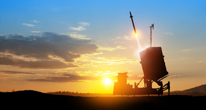 Israel's Iron Dome air defense missile launches. The missiles are aimed at the sky at sunset.