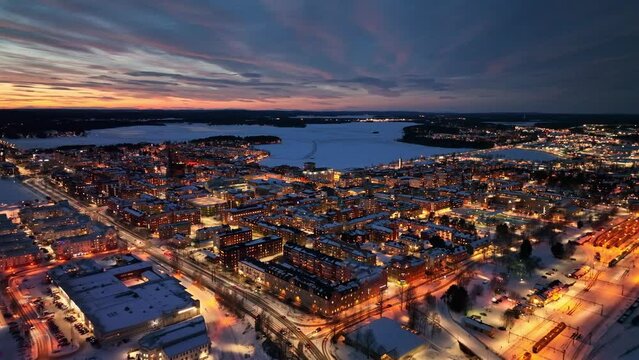 Lule&aring; city at dusk with city lights reflecting on snowy streets and frozen waterways, winter season, aerial view